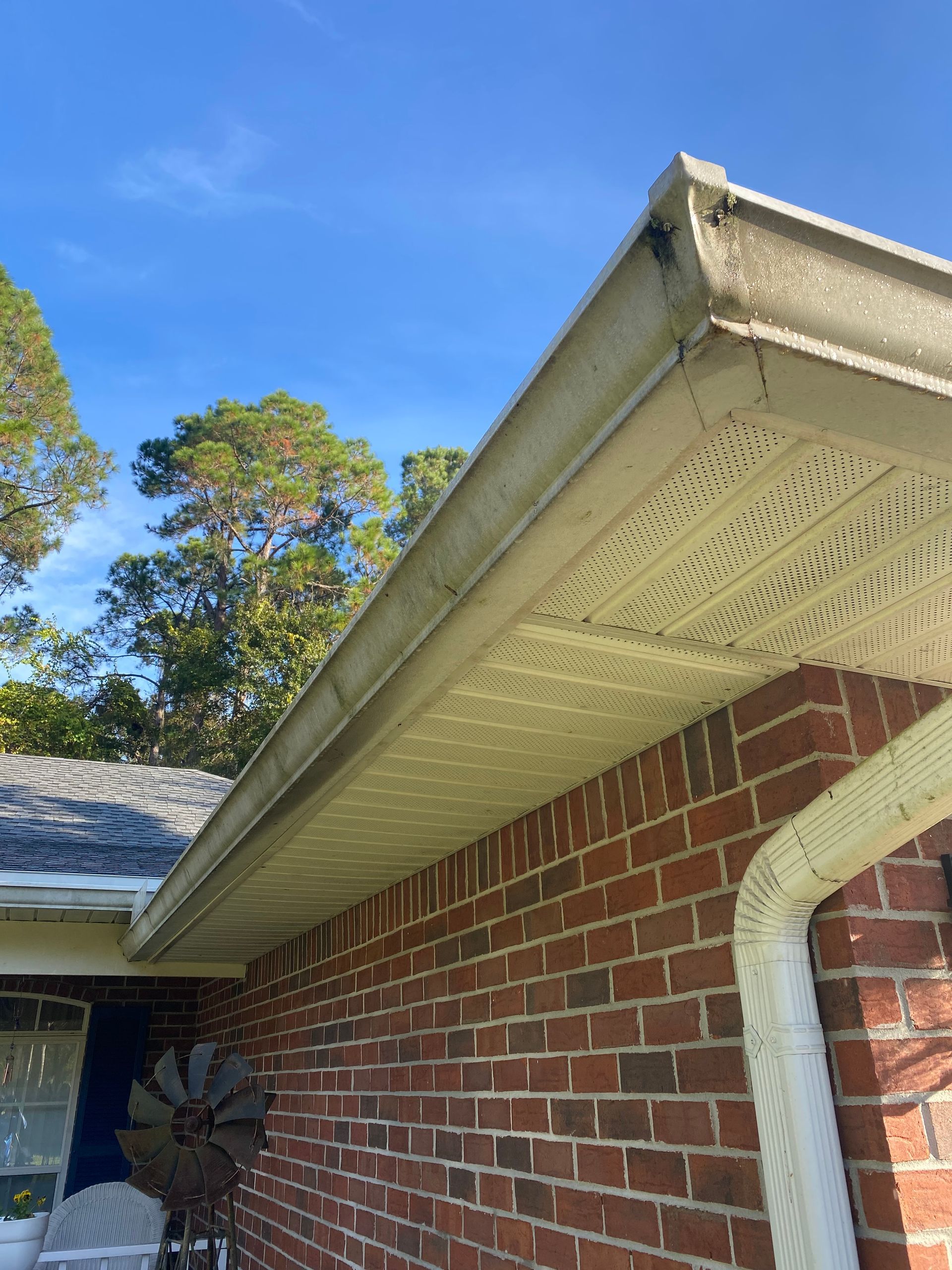 A close up of a gutter on the side of a brick house.