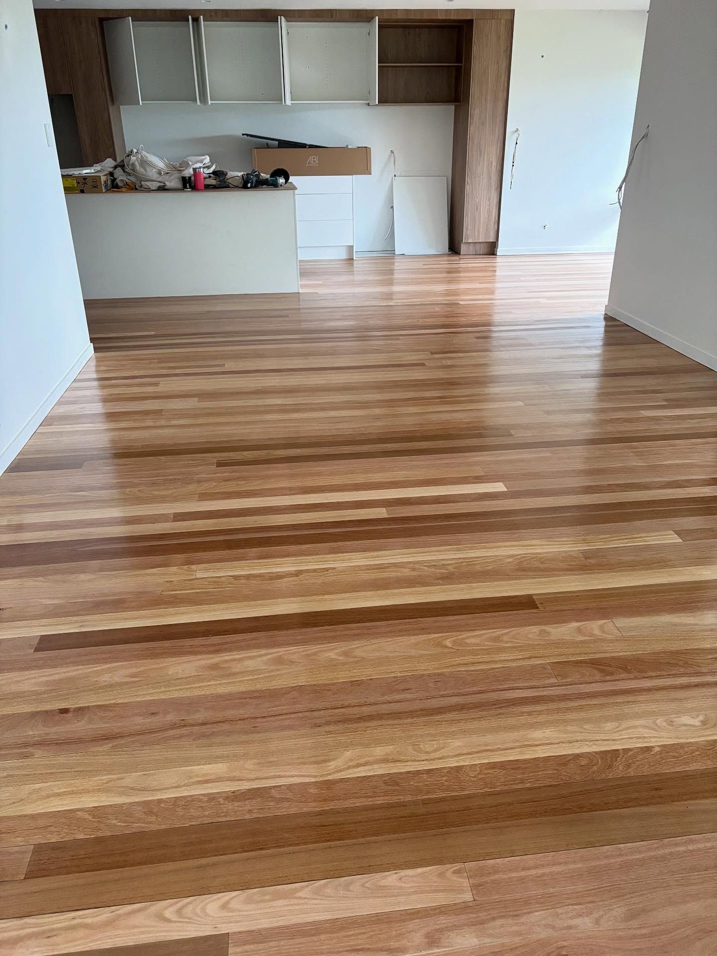Empty unfurnished room with wood-look flooring and a small kitchen area at the back