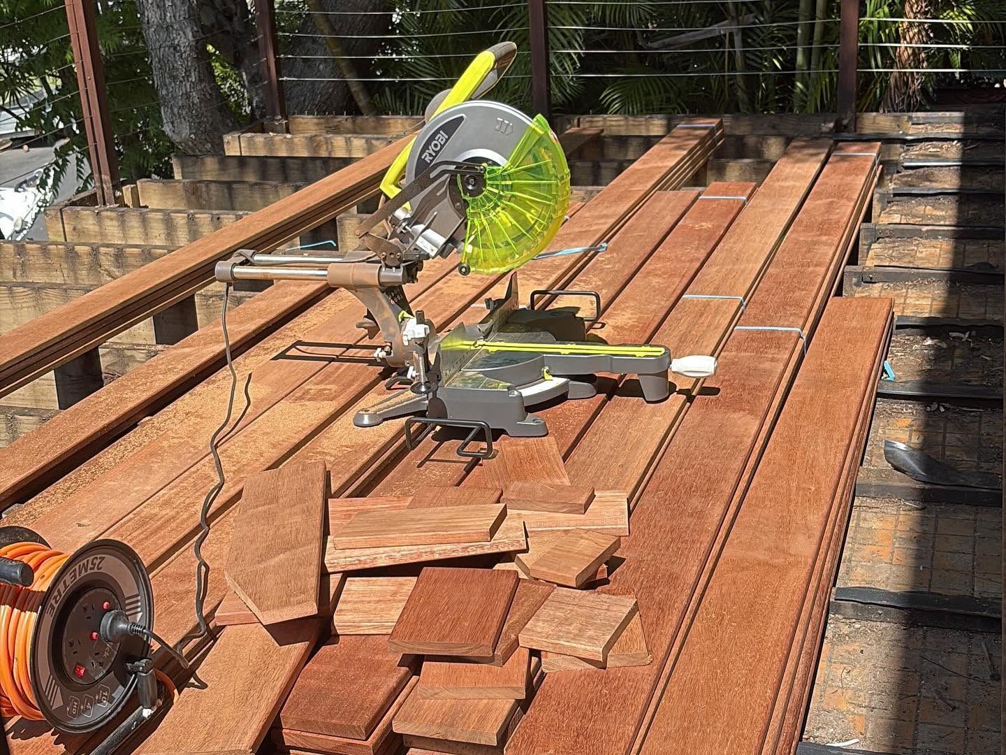 Miter saw cutting stacked pavers on a wooden deck in sunlight
