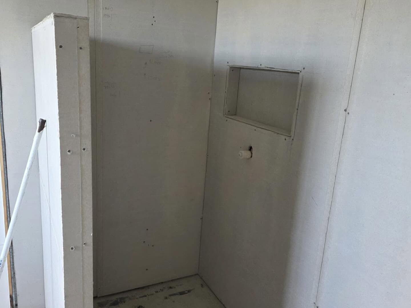 Empty white room with a small wall opening and a hanging fixture, viewed from a doorway.