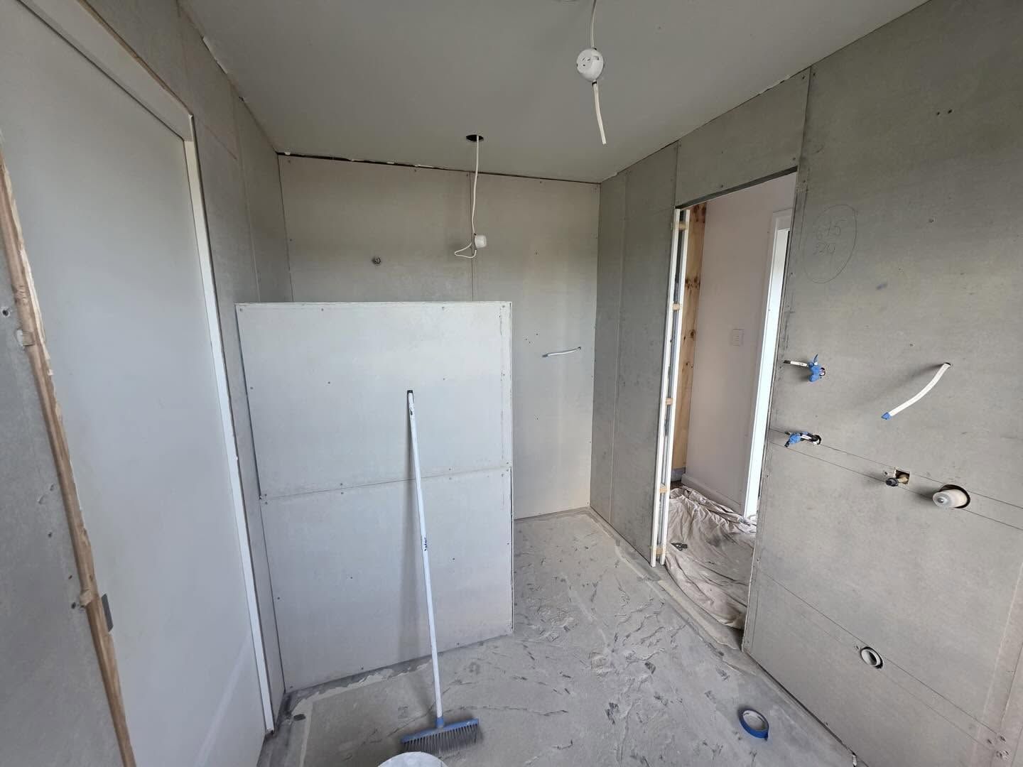 Unfinished room with bare walls, tiled floor, a mop, and a window opening on the right.