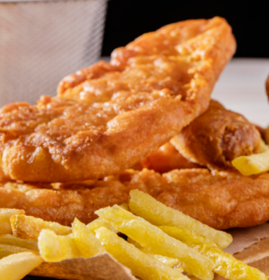 Pescado y patatas fritas: filetes de pescado fritos, dorados y crujientes, apilados con patatas fritas doradas.