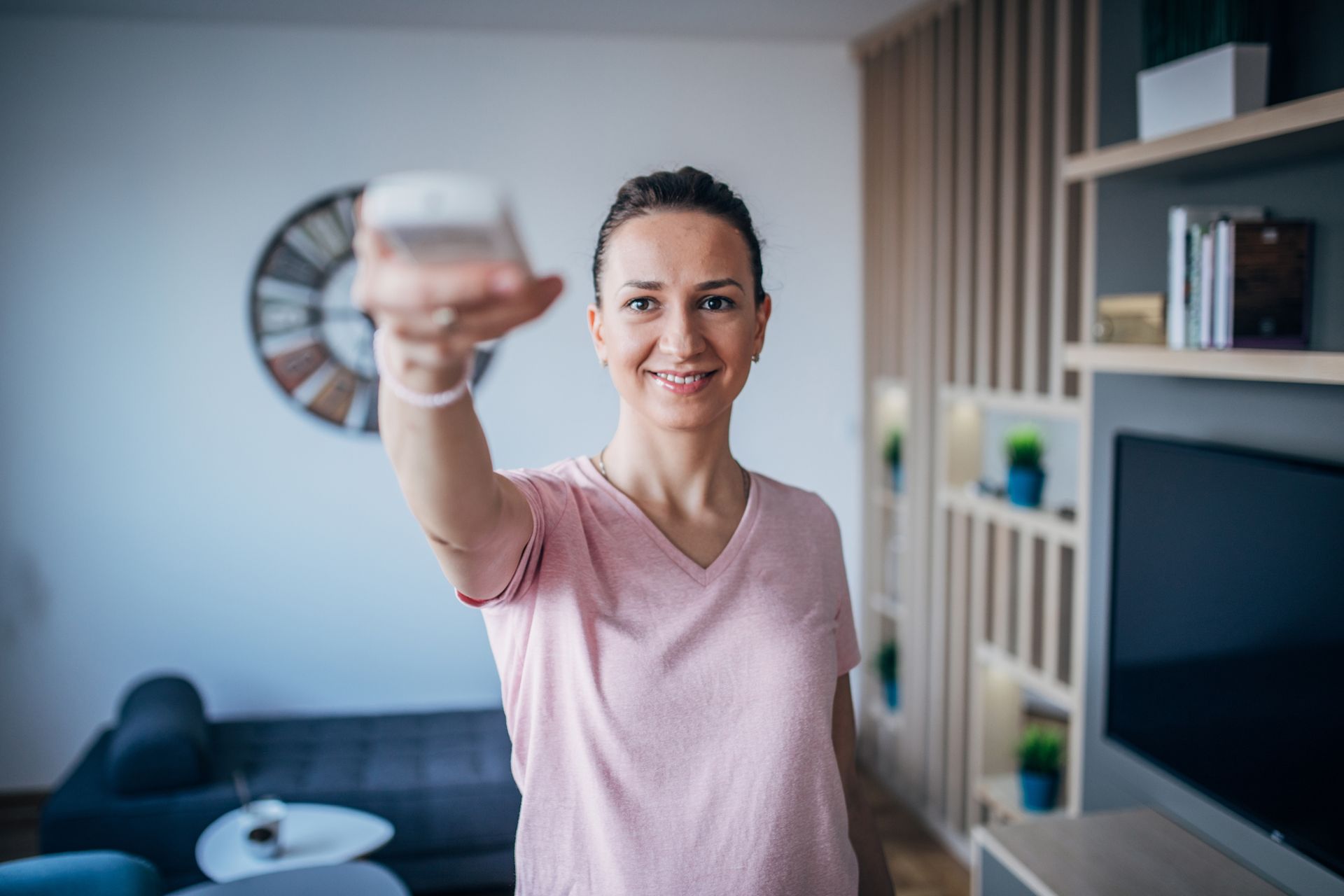 A woman is holding a remote control in her hand in a living room.