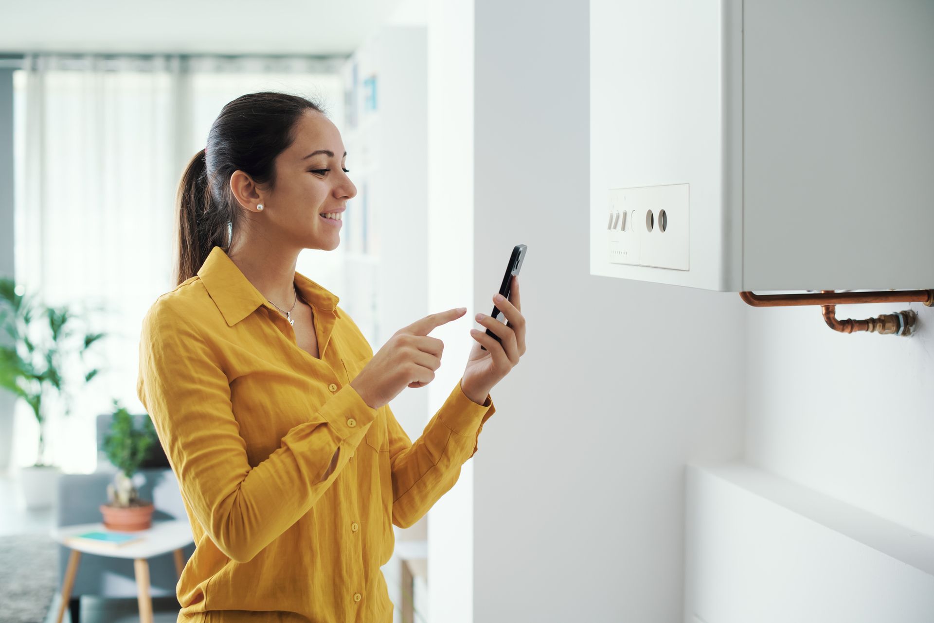 A woman is using a smart phone to control her heating system.