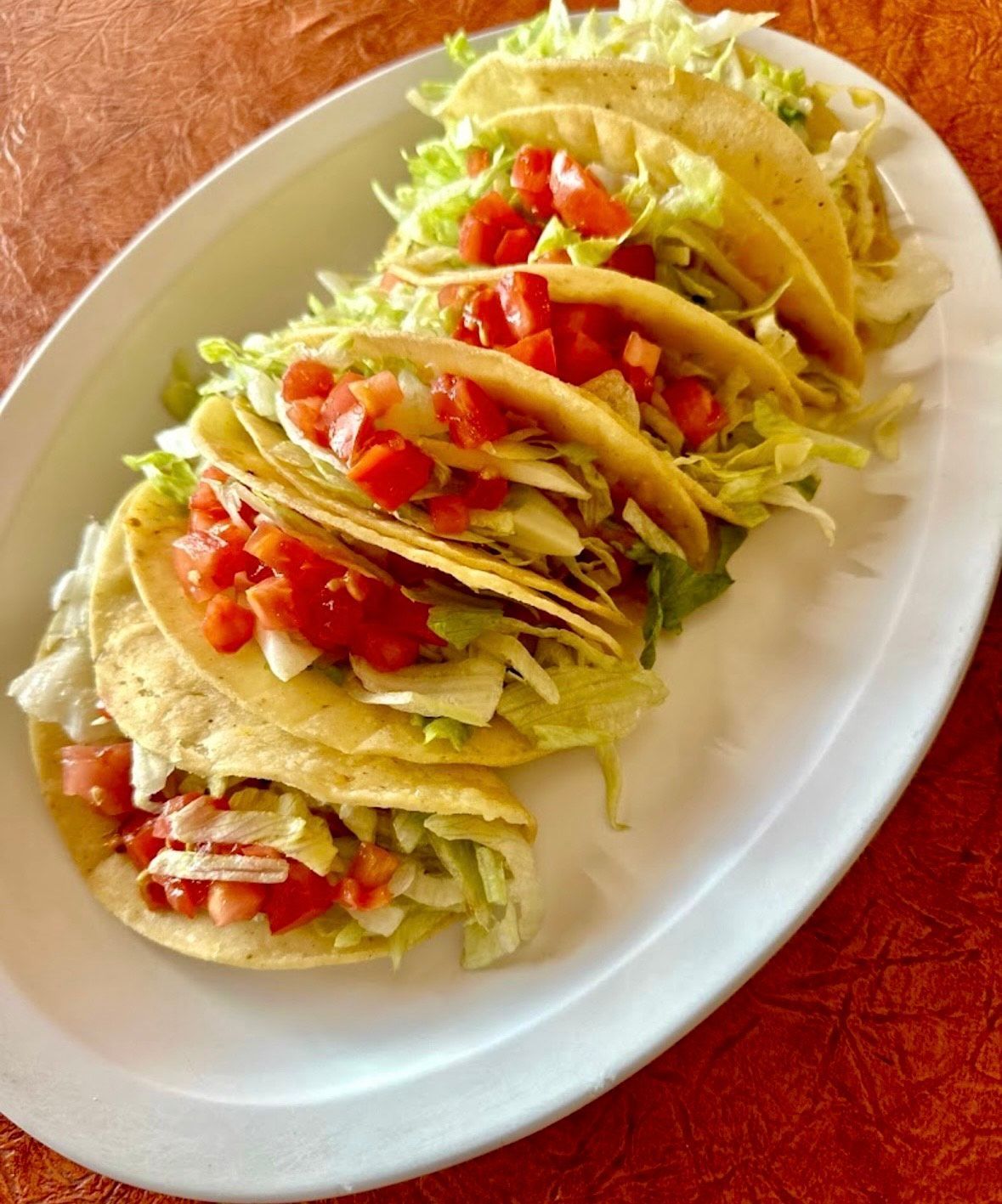 Two tacos on a white plate with onions and cilantro.