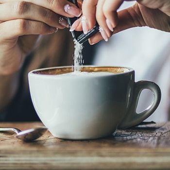 Woman Hand Pours Sugar Into Her Coffee — Cadillac, MI — All Beans Coffee Company