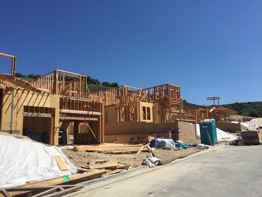Construction site with wooden frames of houses under a blue sky.