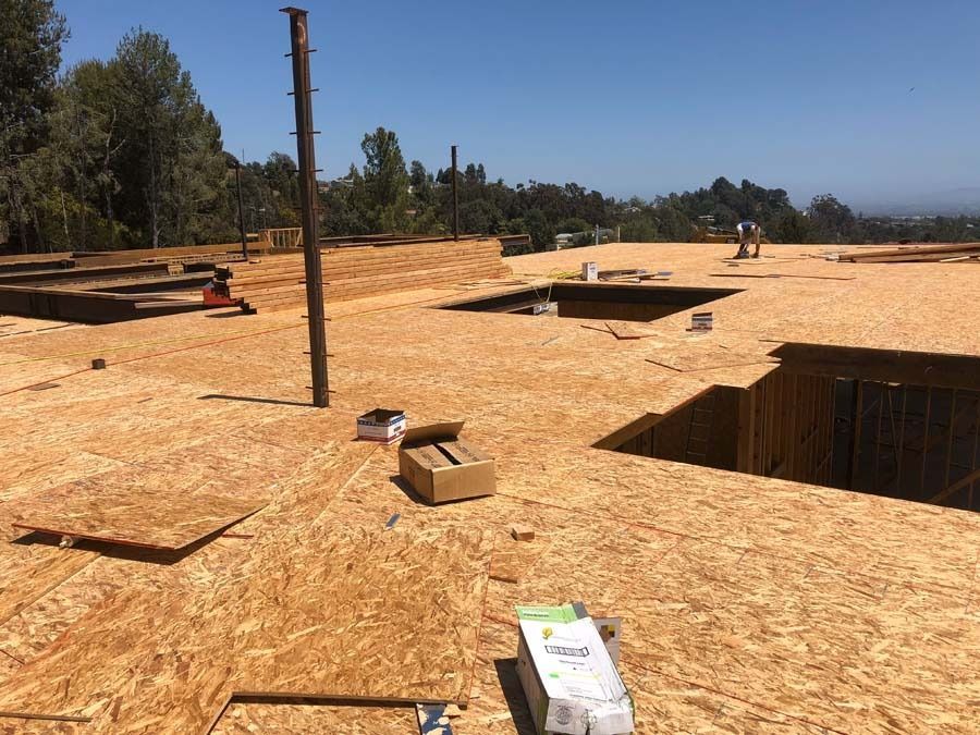 Construction site: Wood subflooring with openings, tools, and a blue sky backdrop.