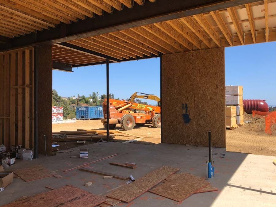 Construction site: interior view, unfinished building frame, machinery, bright blue sky.