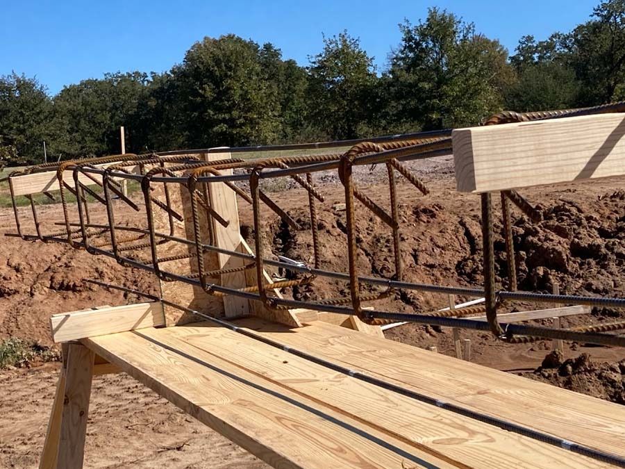 Rebar framework for a concrete foundation, held in place by wooden forms, outdoors.