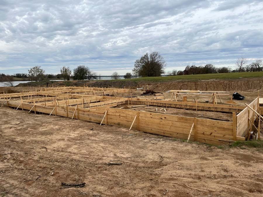 Wooden forms set for a concrete foundation at a construction site on a cloudy day.