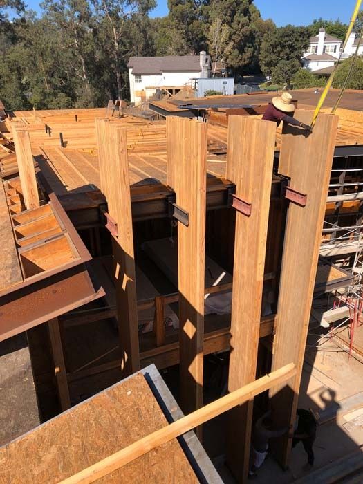 Construction site with wooden beams and workers; daytime.