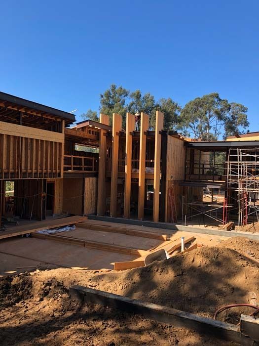 Construction site with wooden framing of a multi-story building under a clear blue sky.