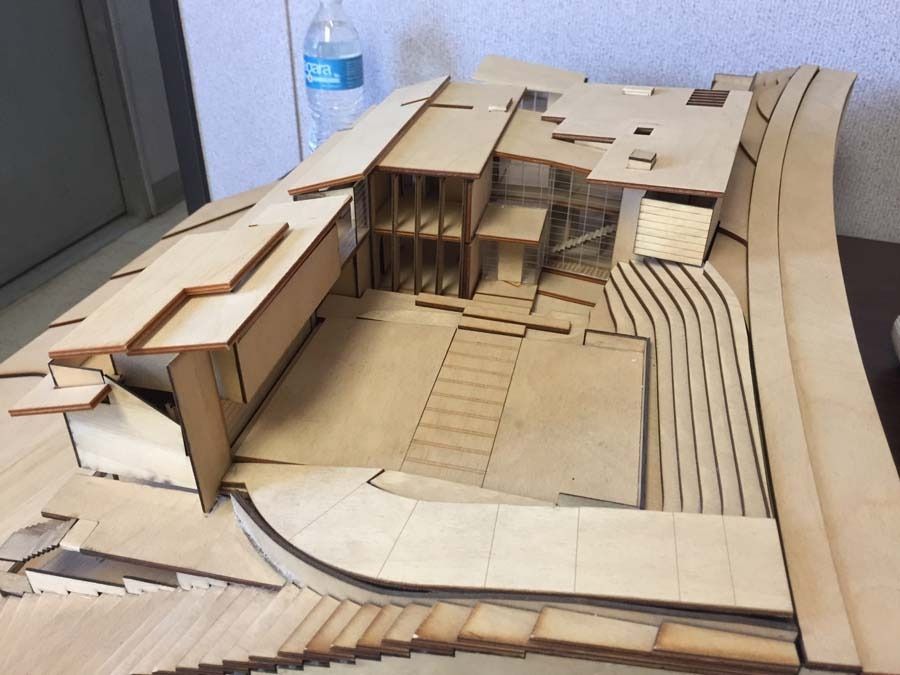 Architectural model of a modern home cut from light wood, showing multiple levels, courtyard, and landscape features.