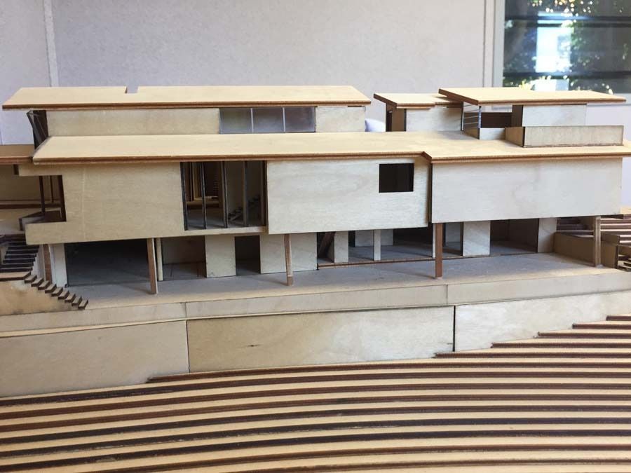 Architectural model of a multi-level building constructed of wood, featuring open spaces and a tiered landscape.