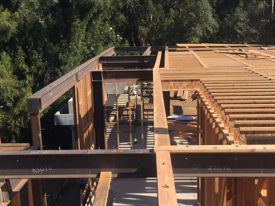 Wooden and steel framework of a building under construction, with visible beams and a partially built roof.