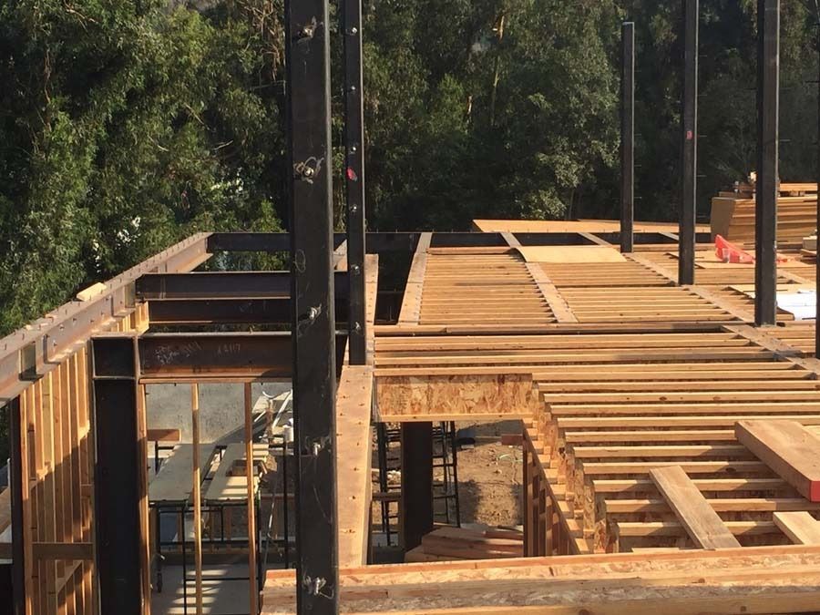 Construction site with wooden floor beams, steel support beams, and partially built structure.