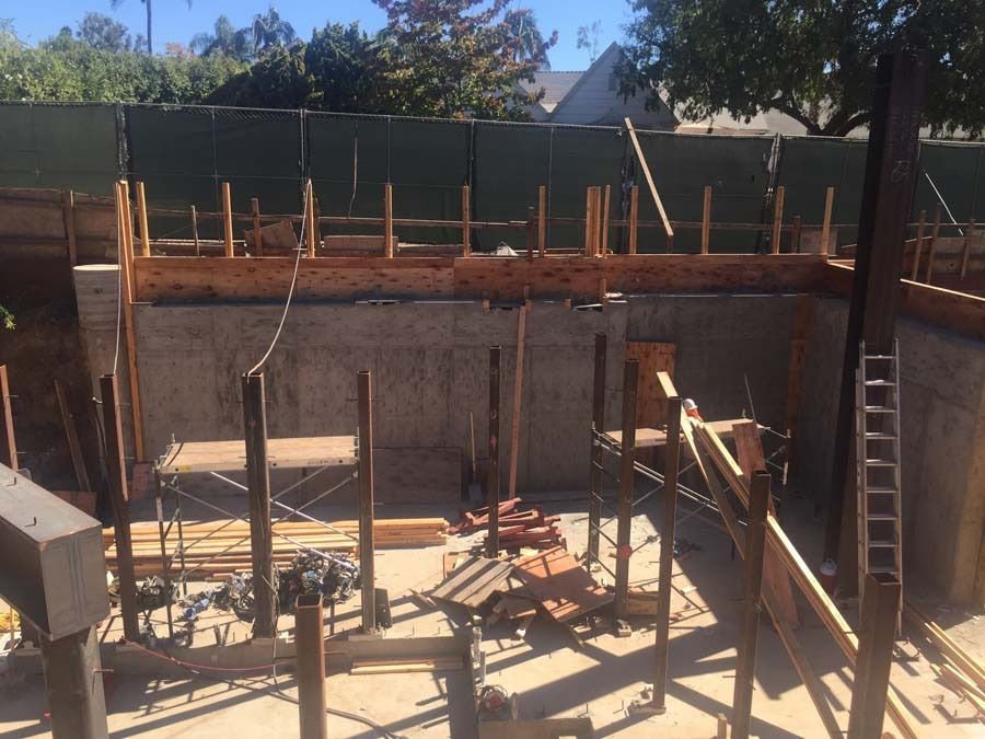 Construction site with concrete walls and wooden frameworks, outdoors under a sunny sky.