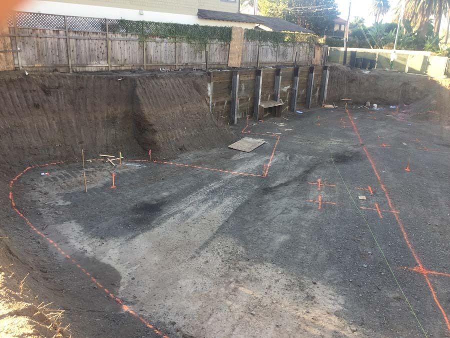 Construction site with excavated dirt, retaining wall, and marked ground.