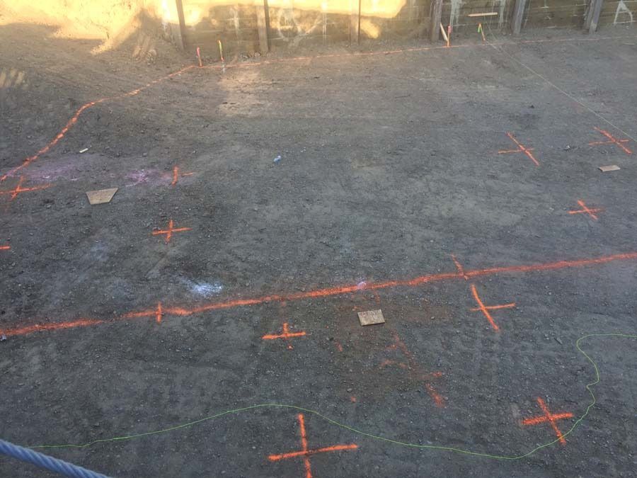 Earth ground marked with orange spray paint for construction layout.
