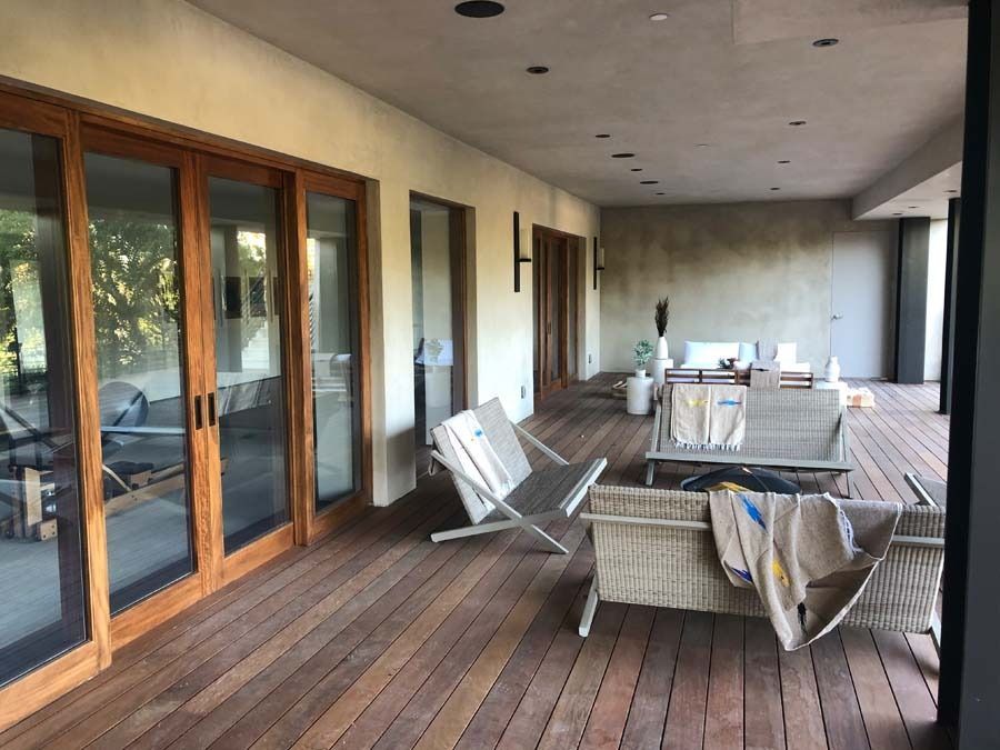 Wooden deck with lounge chairs, sliding glass doors, and beige stucco walls.