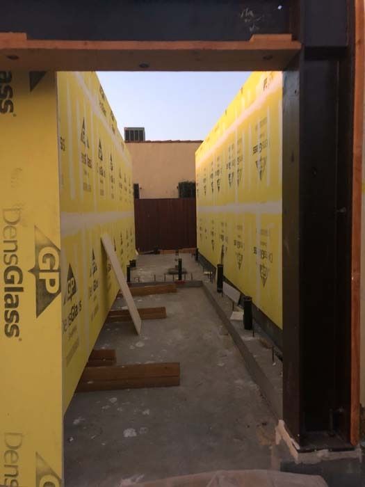 A narrow doorway looking down a corridor with yellow insulated walls under construction.