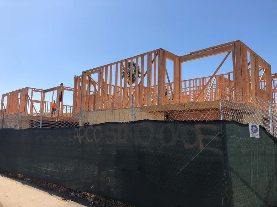 Construction site with wood framing, worker, and green safety fence.