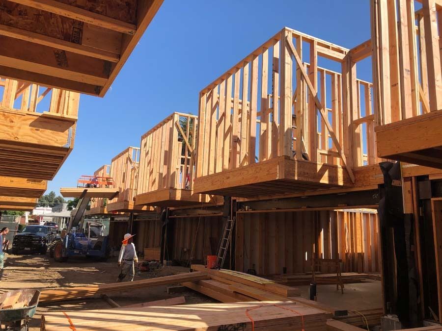 Wooden frames of houses under construction, outdoors on a sunny day.
