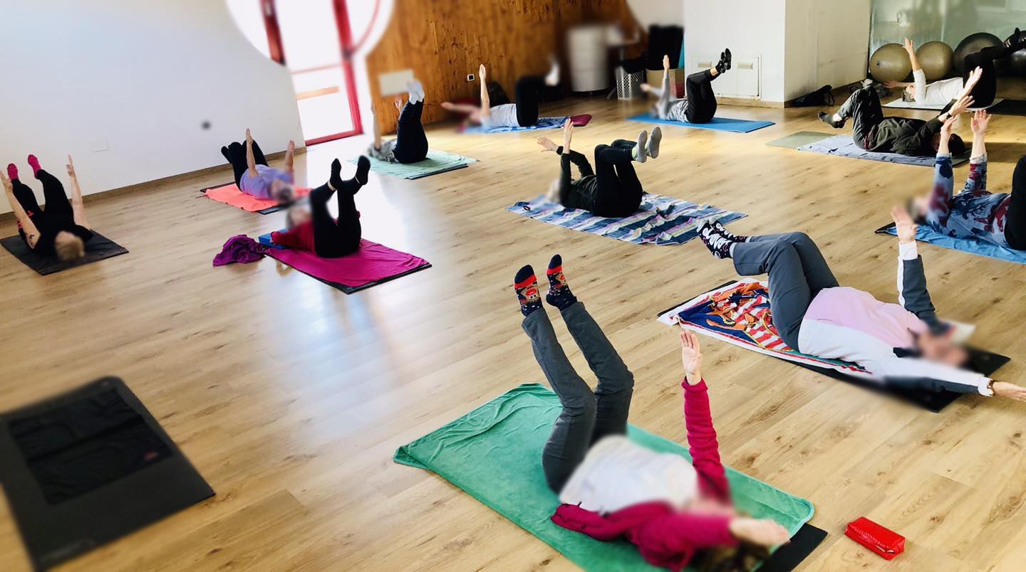 Un gruppo di persone è sdraiato su tappetini da yoga in una stanza.