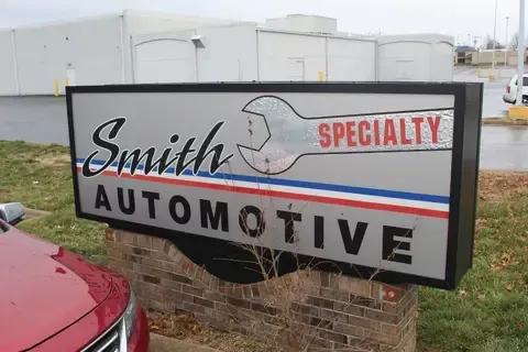 A red car is parked in front of a smith specialty automotive sign.