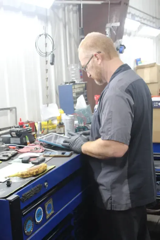 A man is working on a tablet in a garage.
