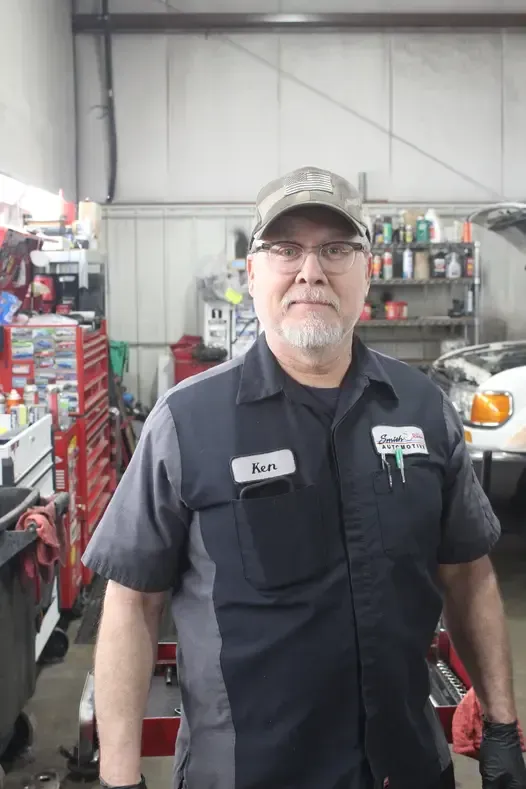 A man in a mechanic 's uniform is standing in a garage.