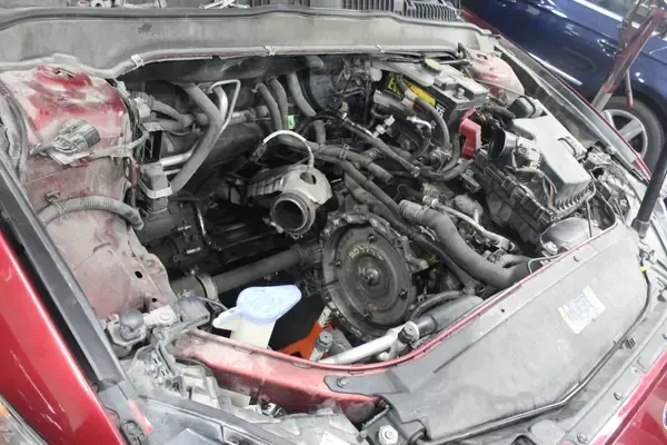 A red car with the hood open and the engine visible