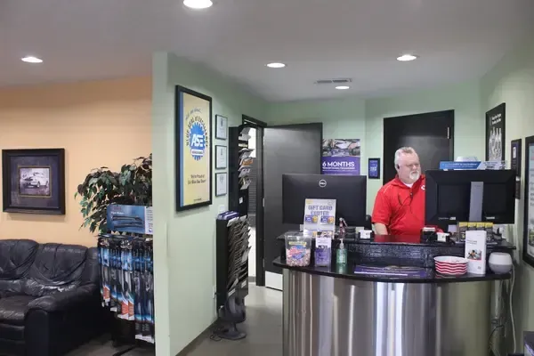 A man in a red shirt is standing at a counter in a room.