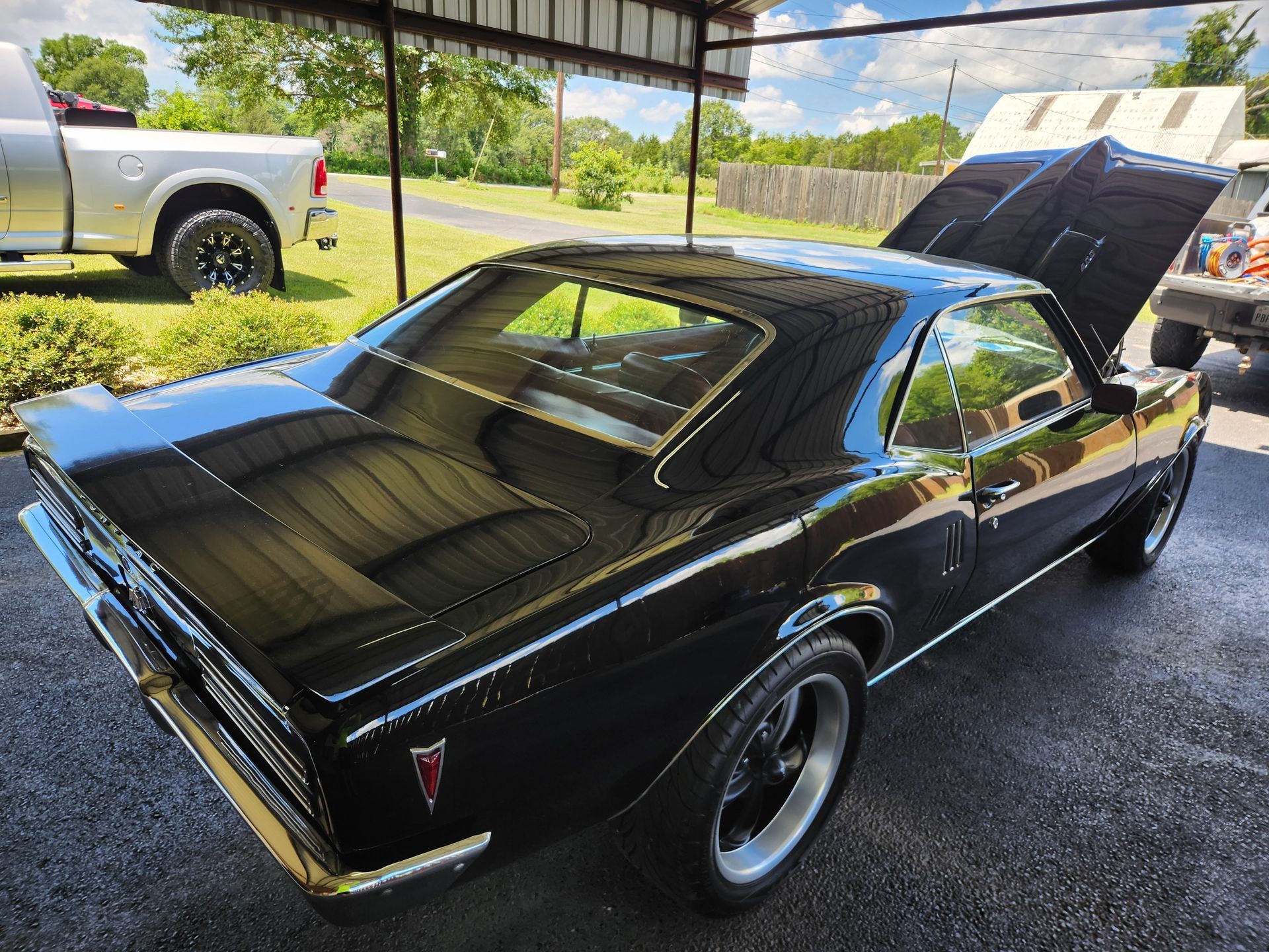 Black classic Pontiac car with the hood open, parked outdoors.