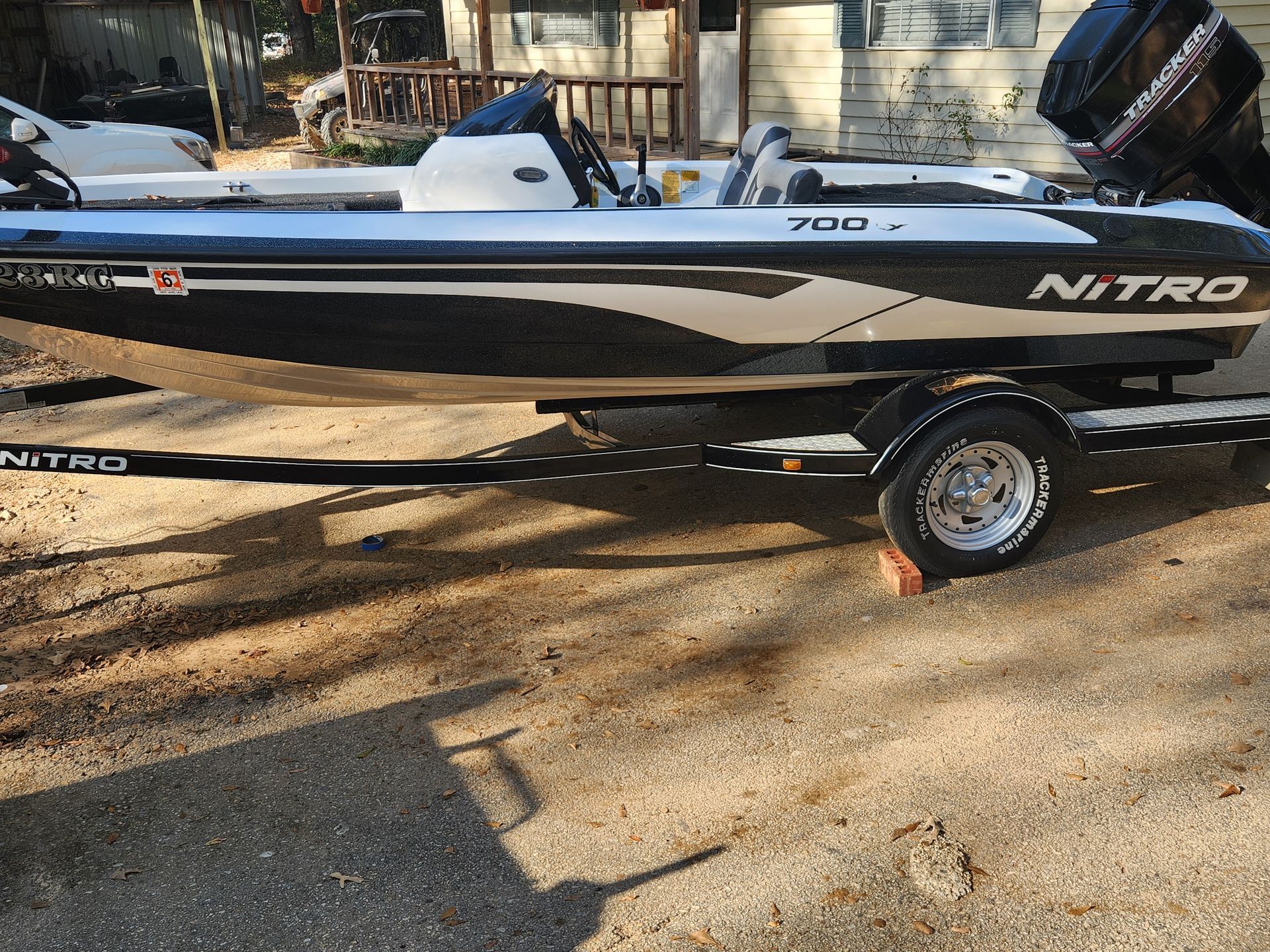 Black and white Nitro bass boat on a trailer, parked on a driveway.