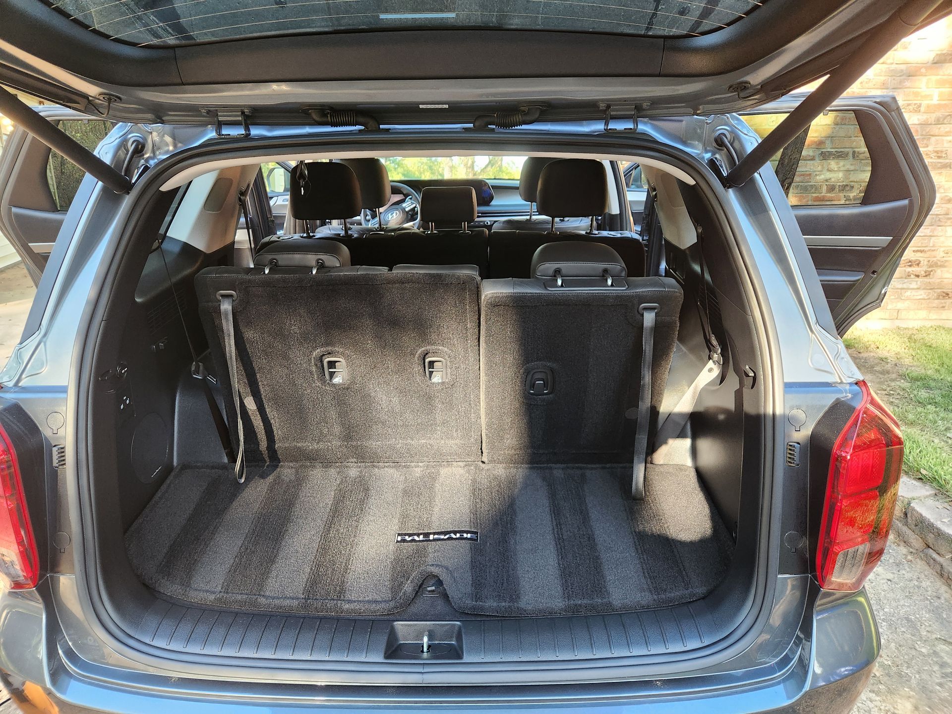 Open gray SUV trunk with folded-down back seats. Carpeted interior with taillight visible.