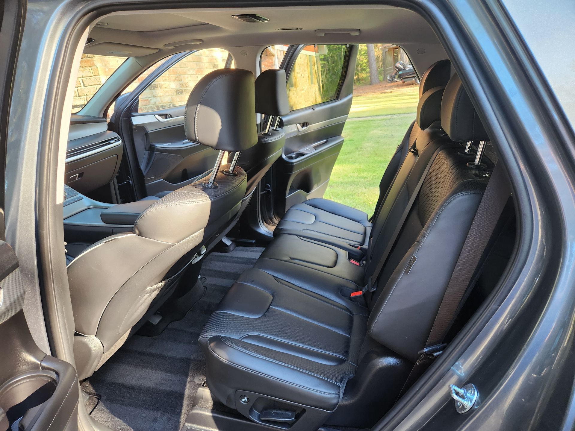 Interior of a gray SUV with black leather seats. The back seats are visible, with the door open.
