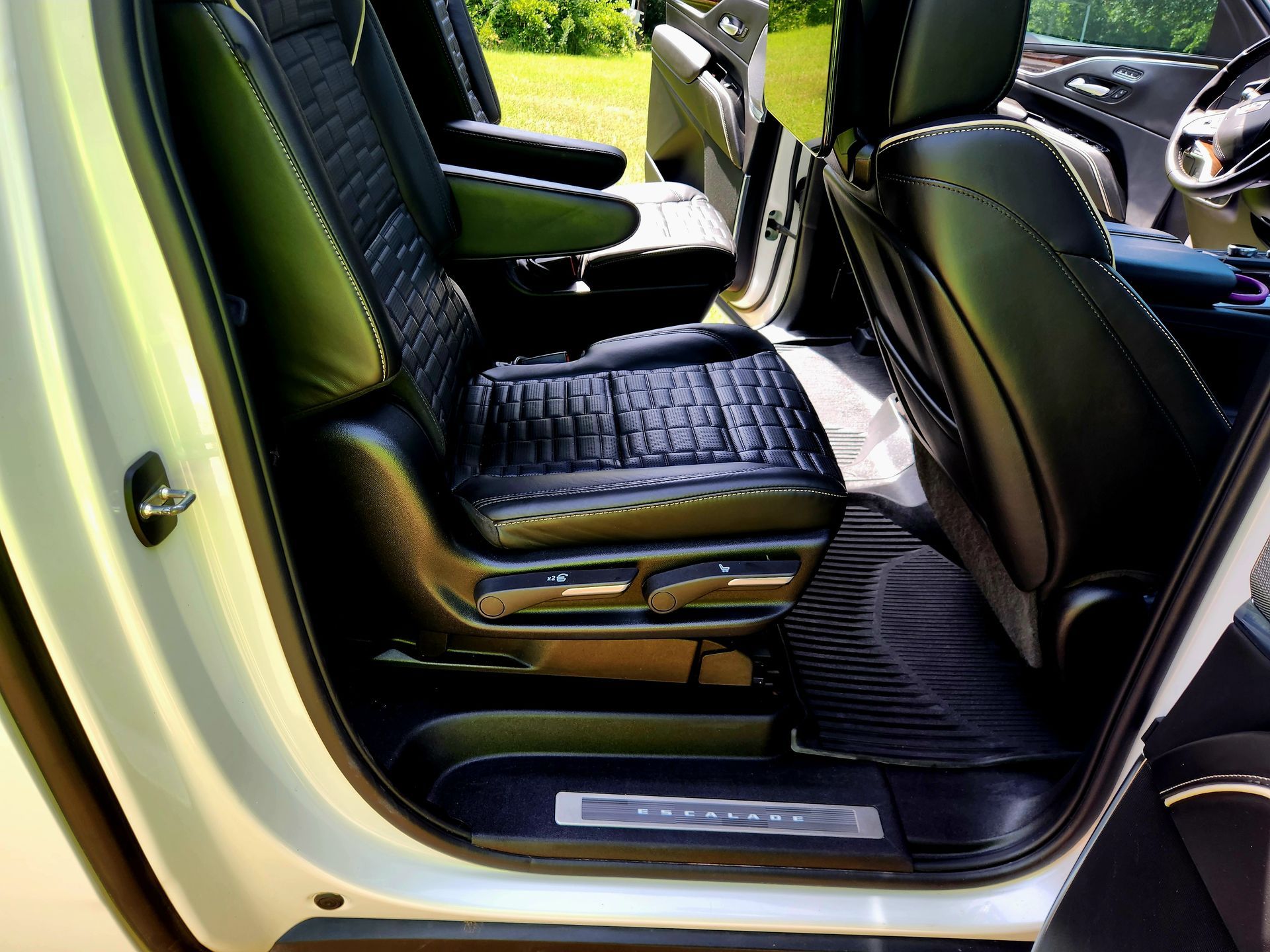 Black leather car seats inside a white vehicle, with a focus on the second-row seating area.