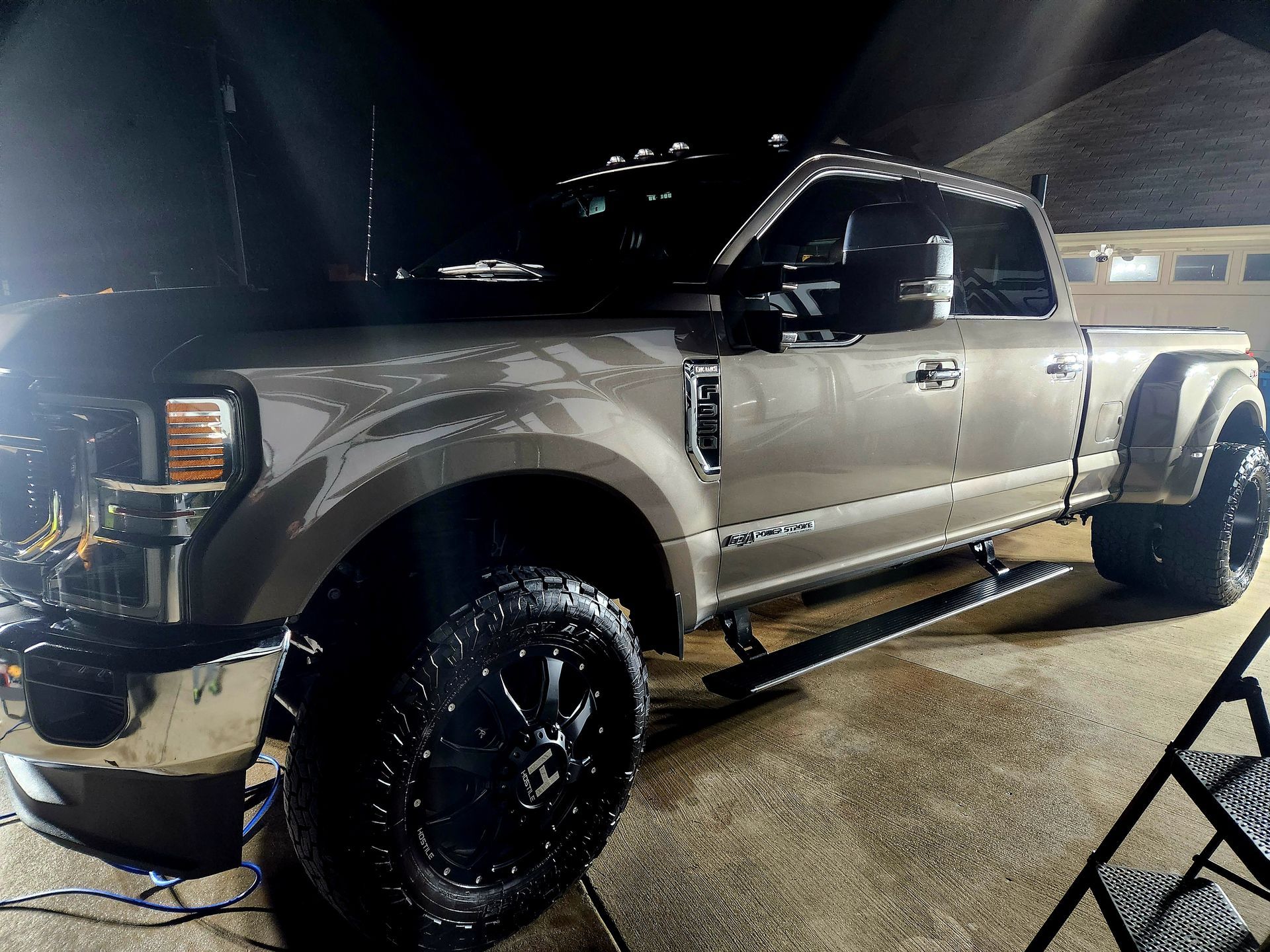 Gray Ford dually truck with black wheels, parked at night.