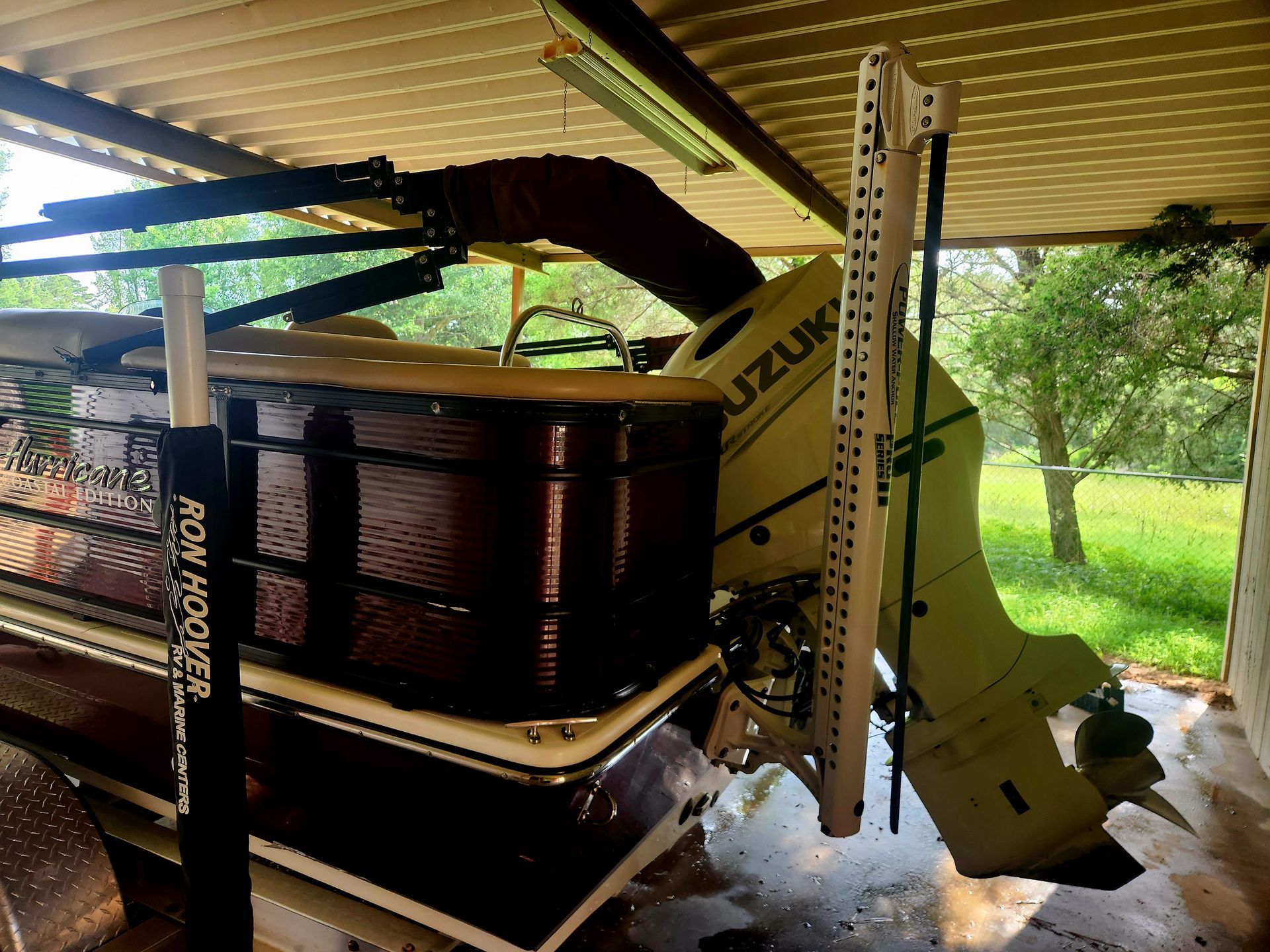 A boat with a Suzuki outboard motor is on a lift under a covered area.