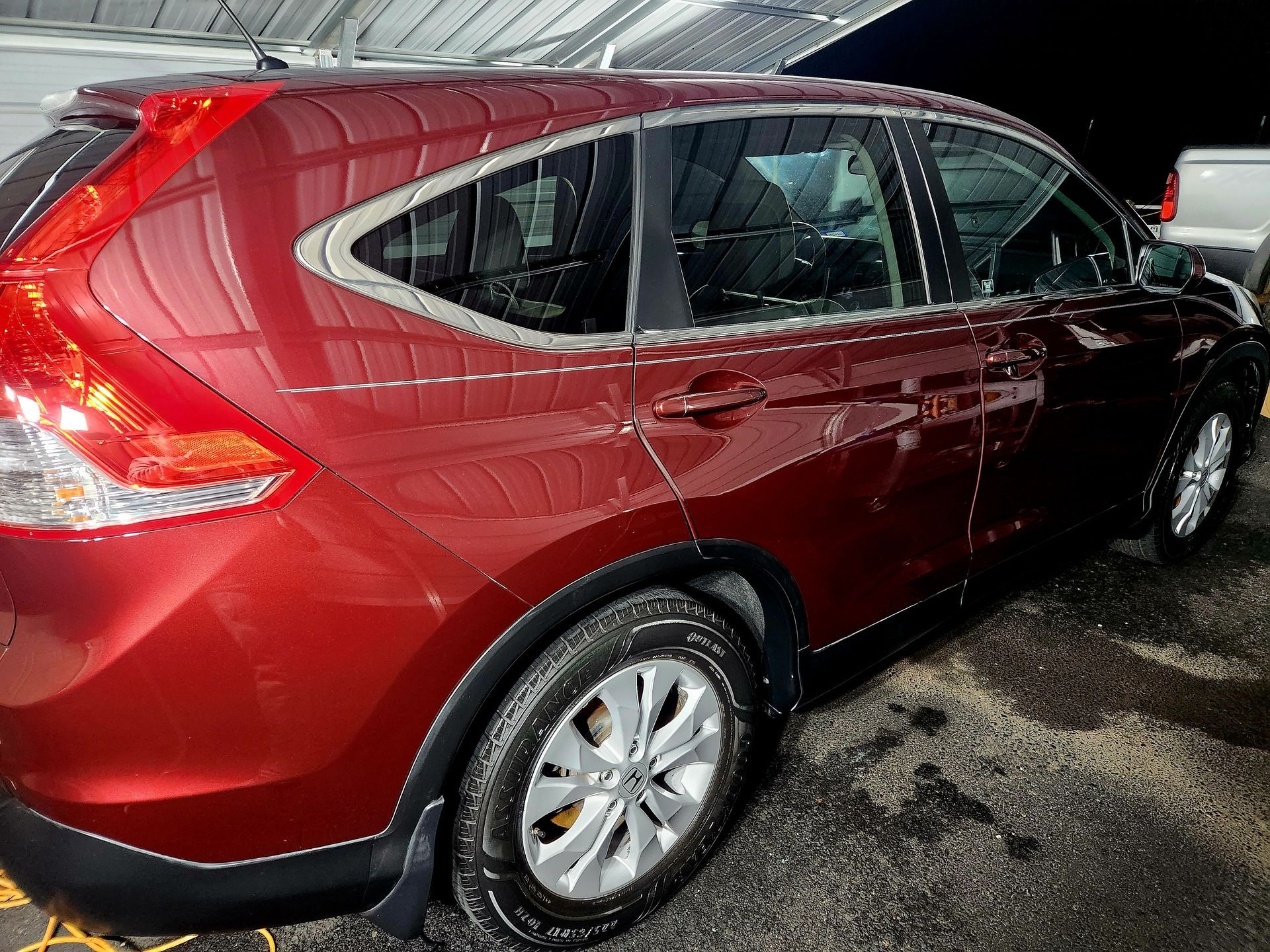 Red Honda CRV parked outdoors; close-up side view showing wheels, windows, and taillight.