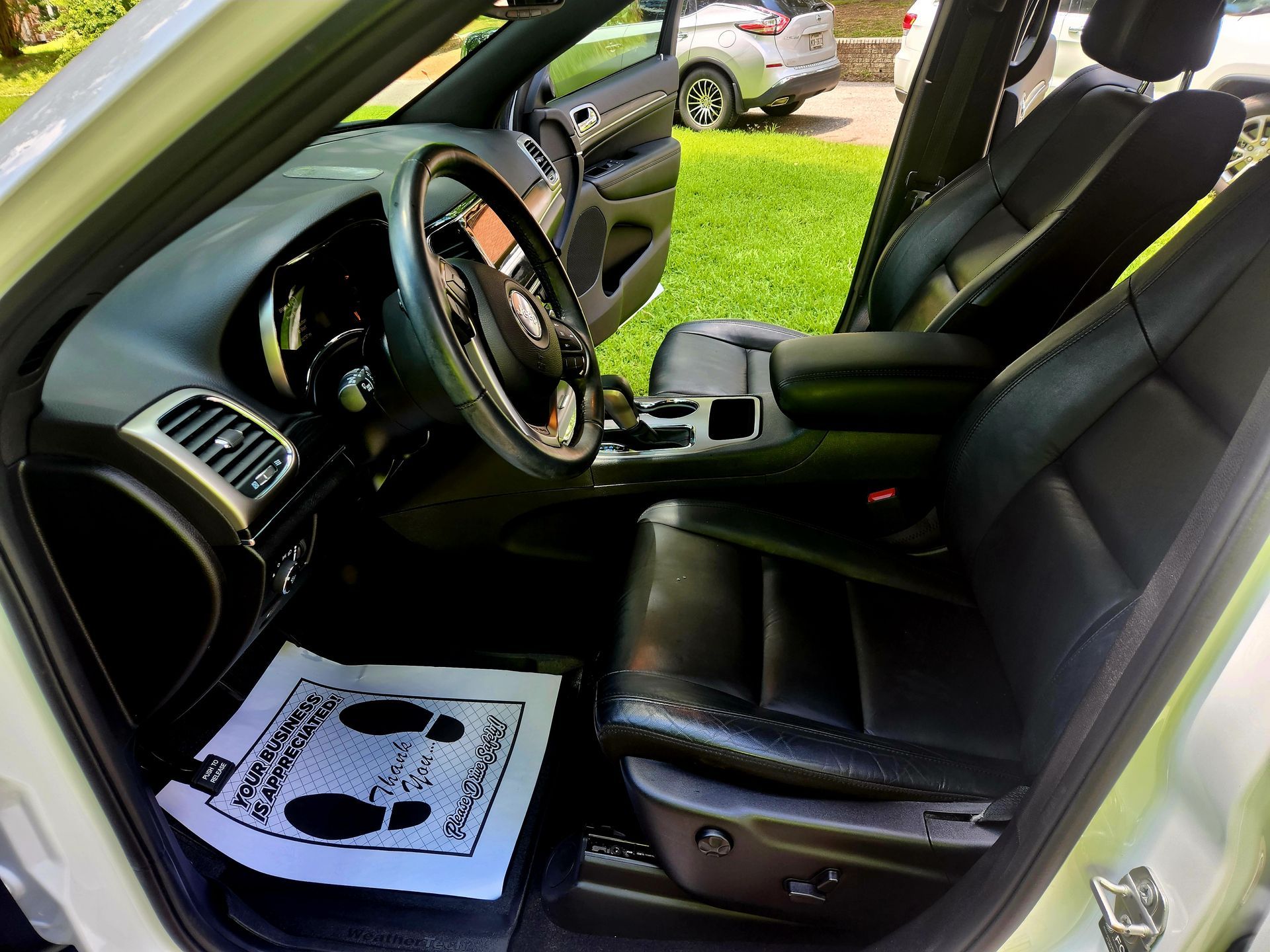 Interior of a white car with black leather seats, steering wheel, and dashboard.