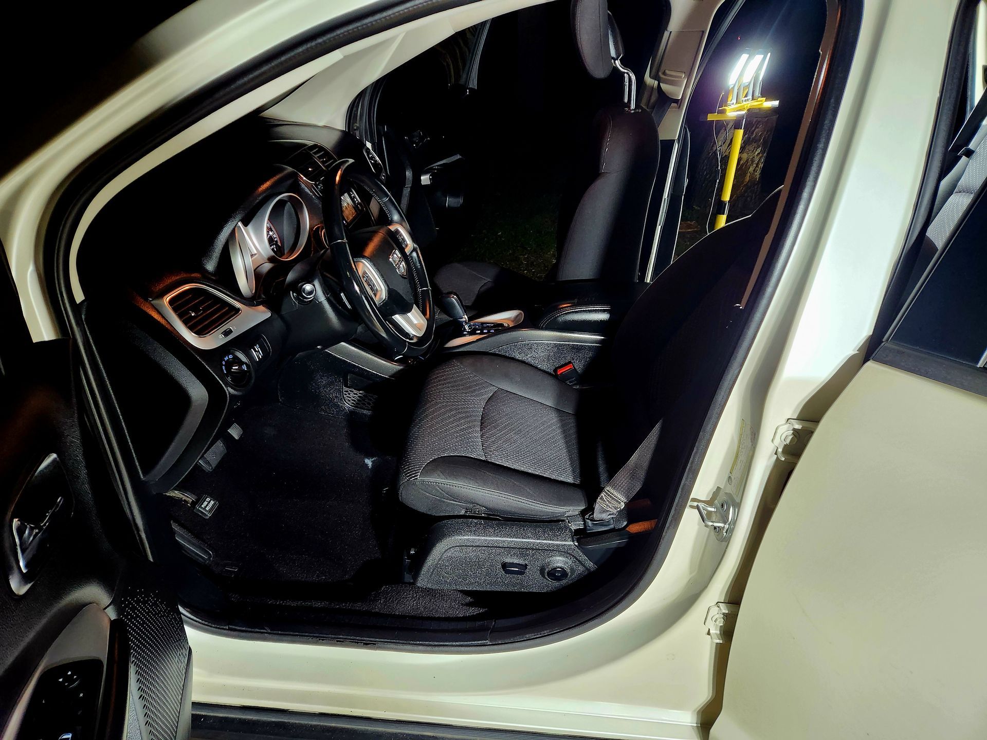 Interior of a car at night, open door, showing driver’s seat, dashboard, and front passenger seat.