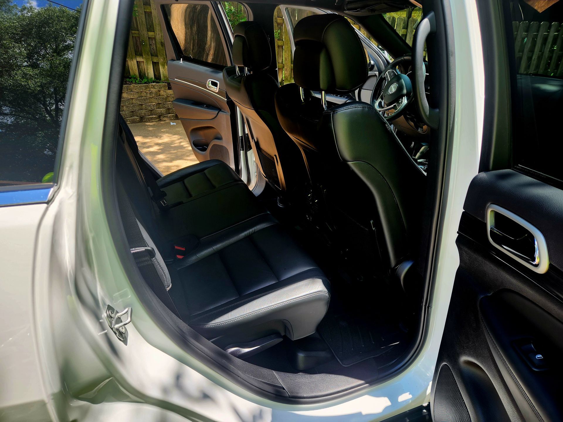 Open rear door of a white SUV showing the interior with black leather seats.