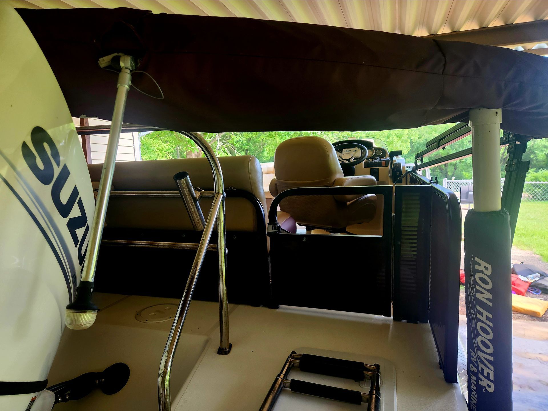 Interior of a pontoon boat with a Suzuki motor, brown canopy, and ladder.