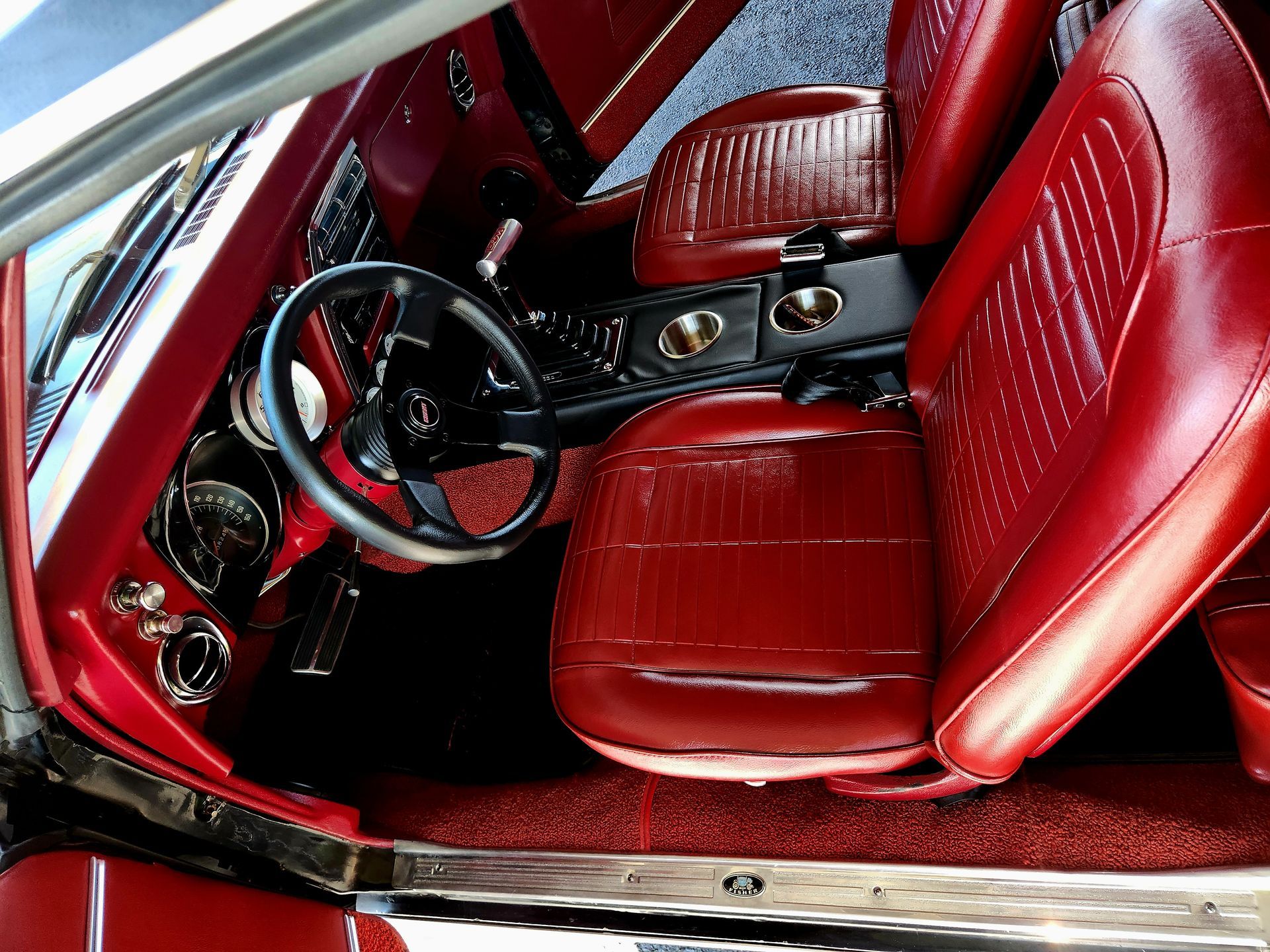 Red leather car interior with a black steering wheel and dashboard.