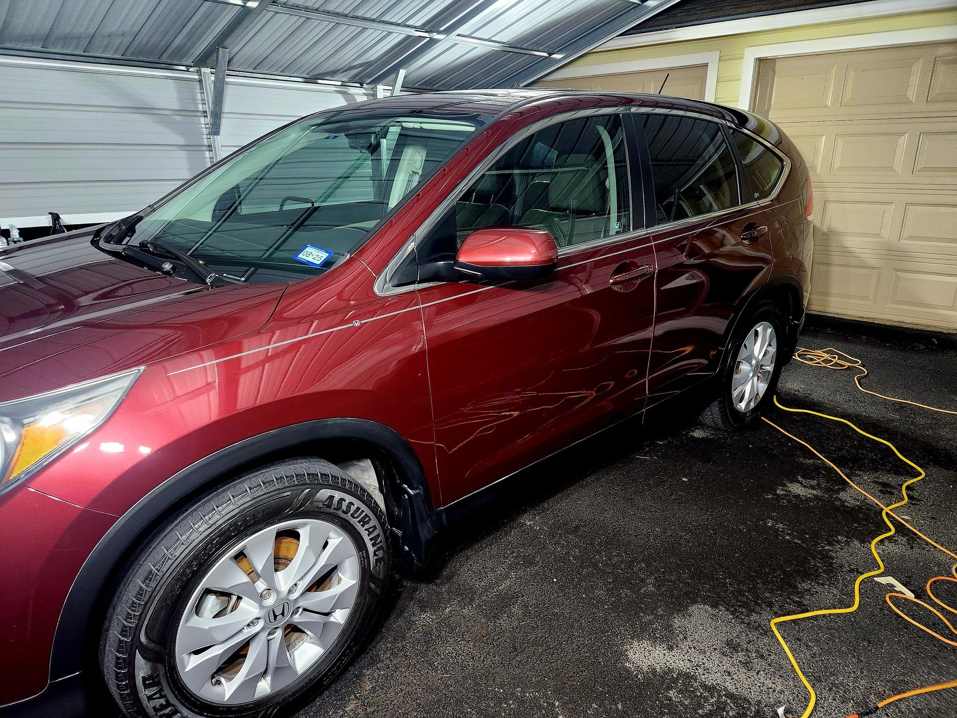 Red SUV parked under a carport, being washed.