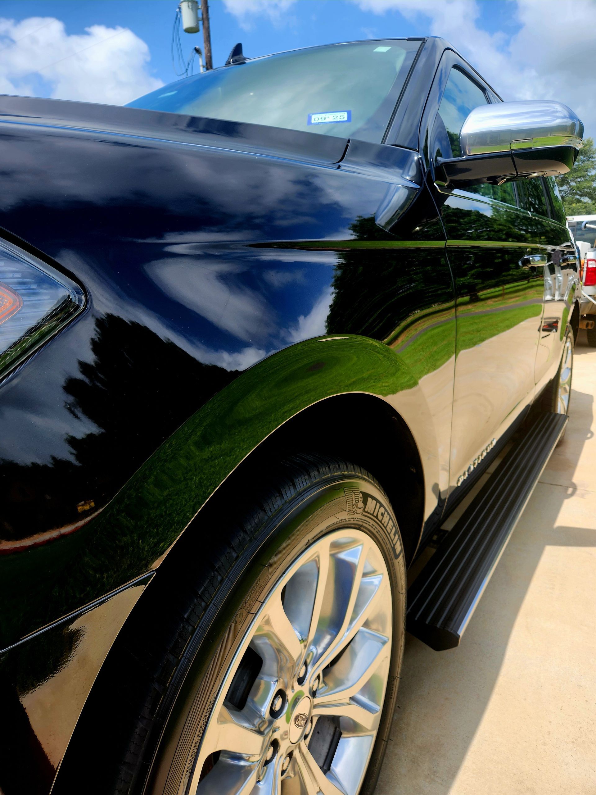 Black Ford Expedition SUV, shiny paint and chrome details, parked outside on a sunny day.
