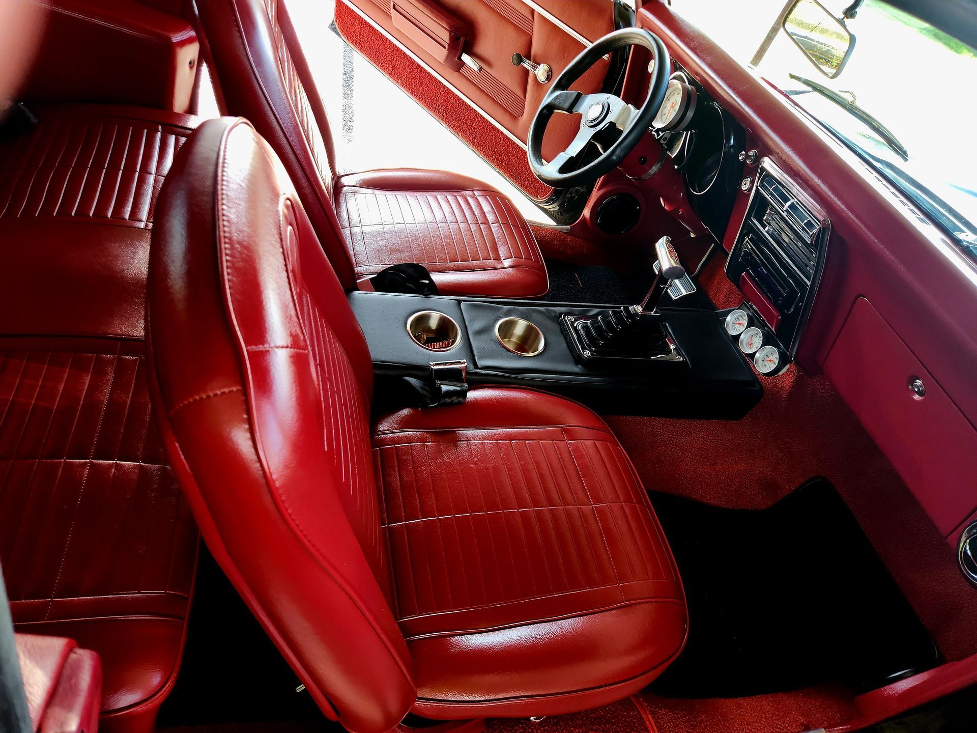 Red interior of a classic car, including seats, dashboard, steering wheel, and center console.